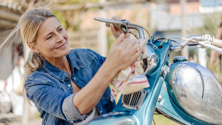 Frau putzt altes Motorrad